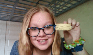 Student hold up a biscuit that she cooked