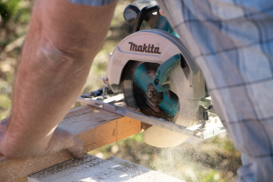 Close up of someone using a circular saw on a piece of lumber