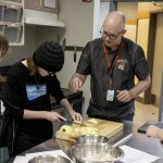A teacher works with three students during a culinary arts class