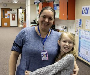 A fourth grader poses for a photo with her mom
